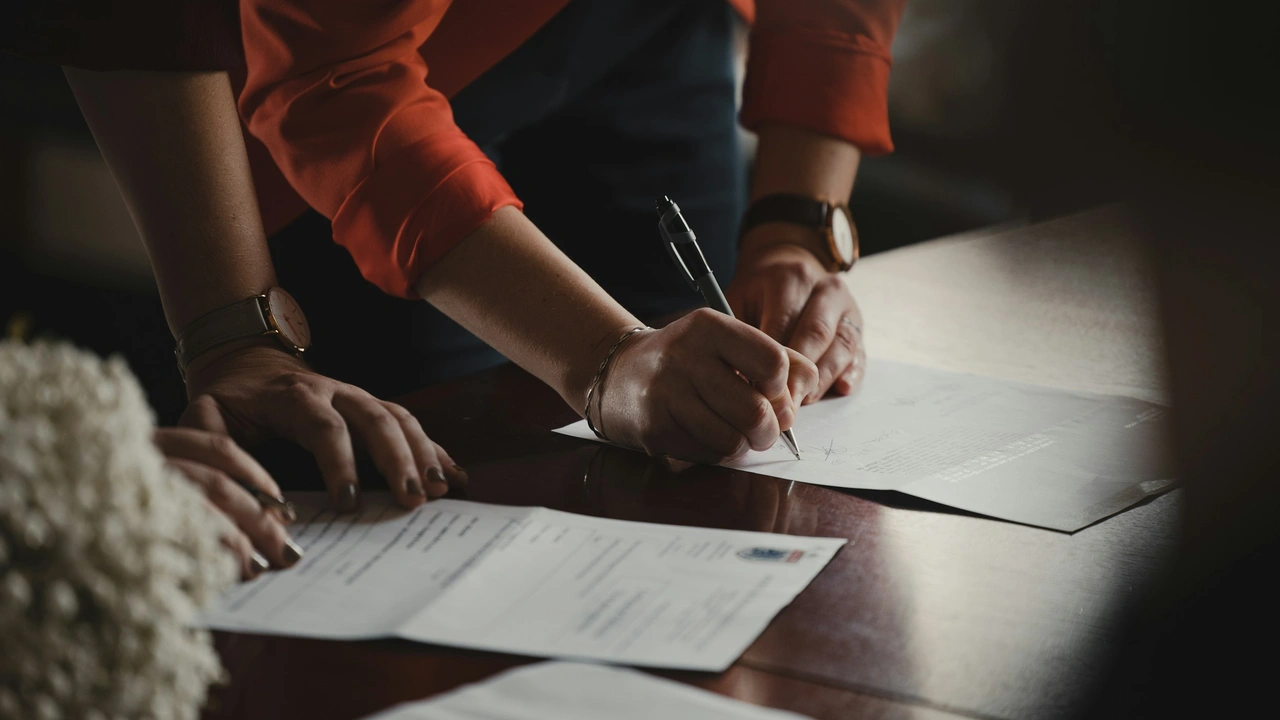 Applicant signing official documents as part of the German visa application process, completing required immigration paperwork at a desk.