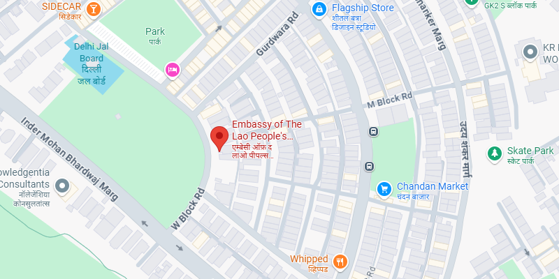 A Google Maps view showing the location of the Embassy of the Lao People's Democratic Republic, marked with a red location pin in the W Block area near Inder Mohan Bhardwaj Marg, New Delhi. Nearby landmarks include Chandan Market, Delhi Jal Board, Sidecar, and Whipped café. The surrounding streets and parks are also labeled.